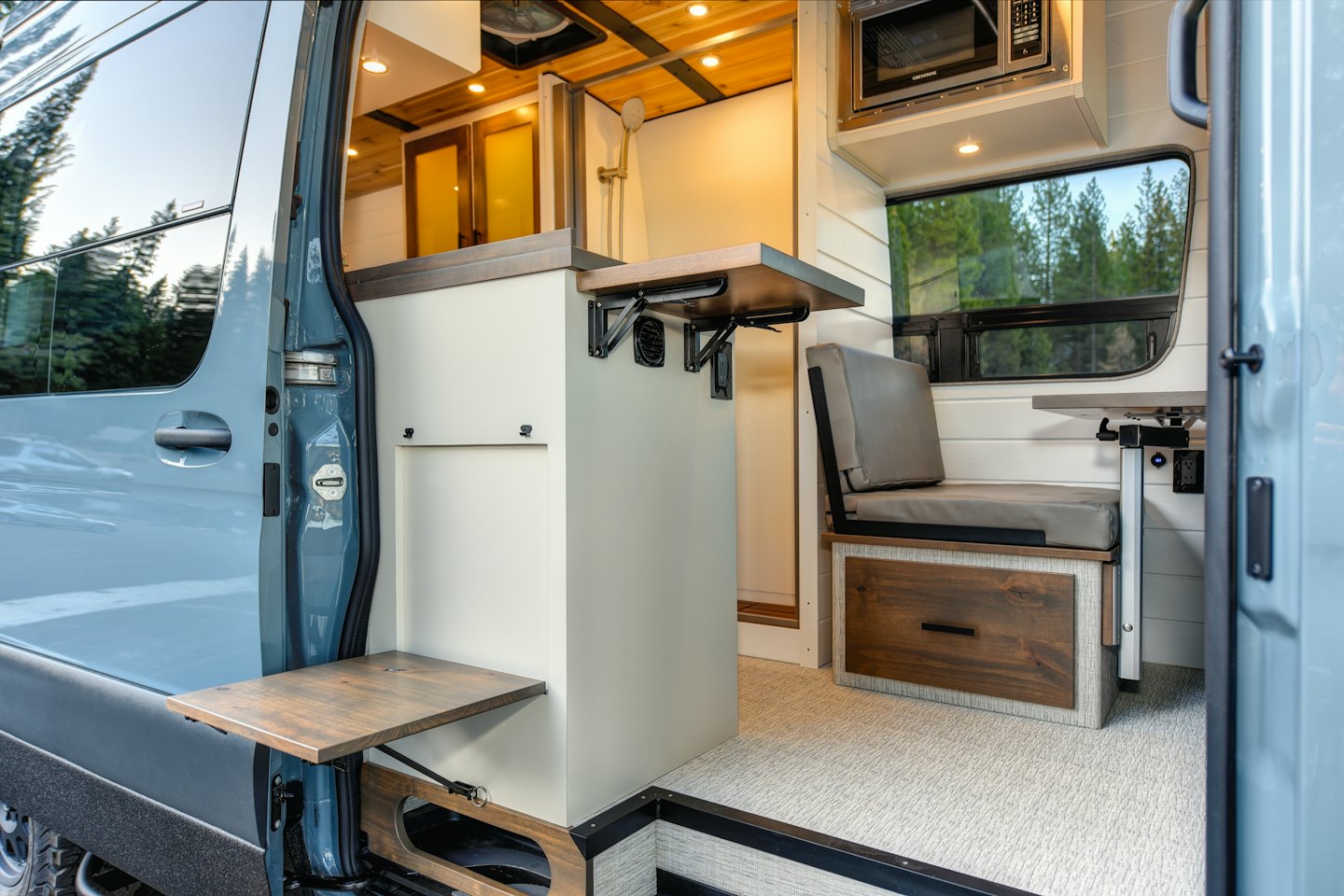 Modern camper van living space with kitchen and fold-out table.