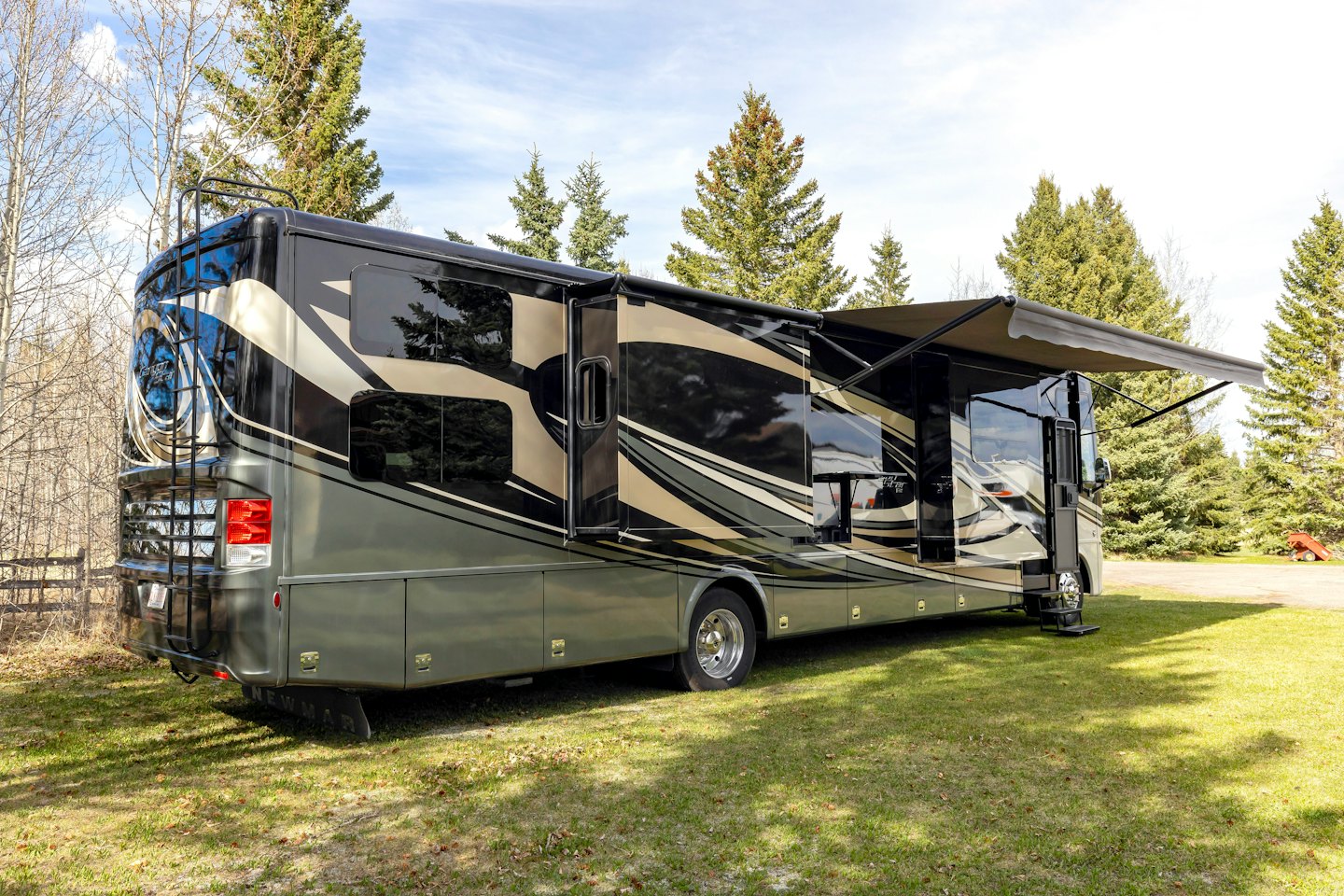 A black and gold motorhome parked on green grass.