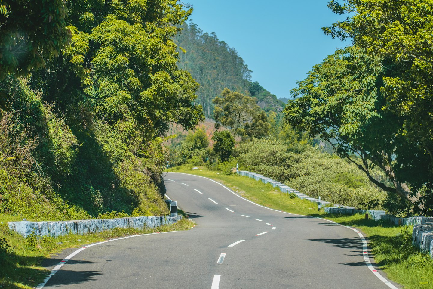Winding mountain road through green hills on a sunny day.